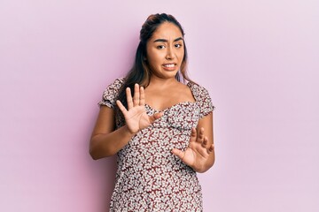 Young latin woman wearing casual clothes disgusted expression, displeased and fearful doing disgust face because aversion reaction. with hands raised