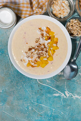 healthy smoothie bowl with mango, coconut and nuts, vertical