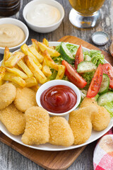 lunch with chicken nuggets, french fries, fresh salad and beer