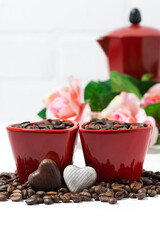 red cup with coffee beans and chocolate candies on white background, vertical closeup
