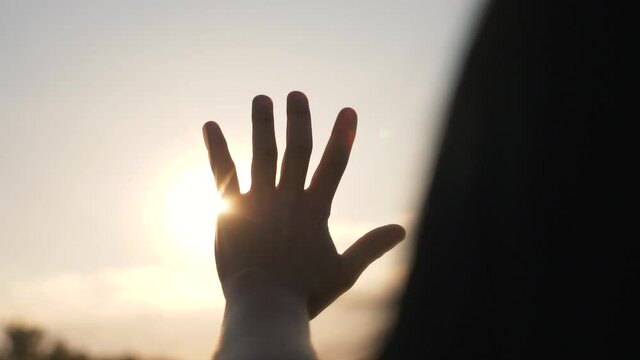 Hand of happy girl at sunset. Sunset between the hands of girl. Happy girl with long hair dreamily stretches out her hand to the sun. Child's dream hand to the sun. happy family concept