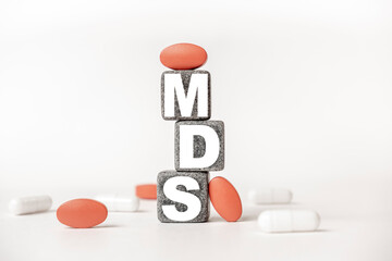 a group of white and red pills and cubes with the word MDS Myelo dysplastic syndrome on them, white background. Concept carehealth, treatment, therapy.