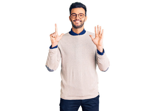 Young handsome hispanic man wearing elegant clothes and glasses showing and pointing up with fingers number seven while smiling confident and happy.