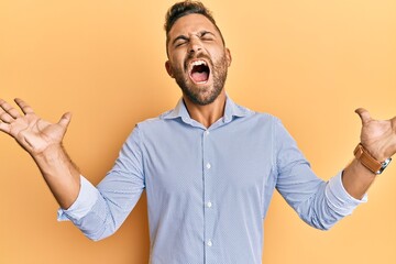 Handsome man with beard wearing casual clothes celebrating mad and crazy for success with arms...