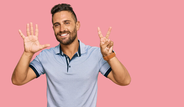 Handsome man with beard wearing casual clothes showing and pointing up with fingers number seven while smiling confident and happy.