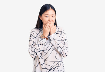 Young beautiful chinese woman wearing casual shirt laughing and embarrassed giggle covering mouth...