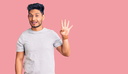 Naklejka premium Handsome latin american young man wearing casual tshirt showing and pointing up with fingers number four while smiling confident and happy.