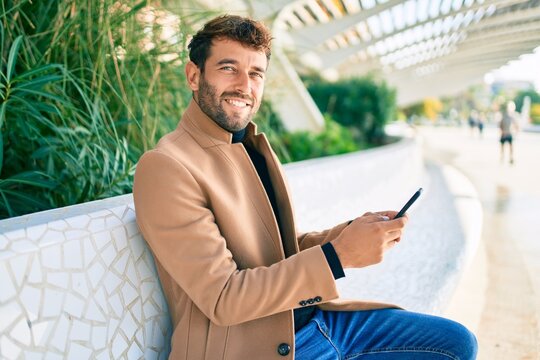 Handsome business man wearing elegant jacket using smartphone smiling happy outdoors