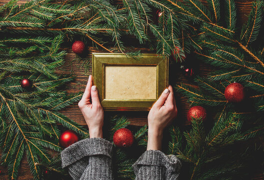 Female hands hold photo frame next to Christmas decoration