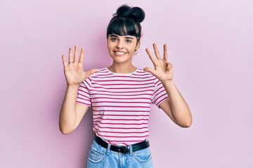 Young hispanic girl wearing casual clothes showing and pointing up with fingers number nine while...