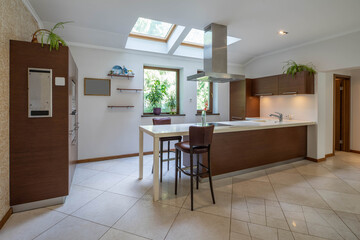 Contemporary interior of kitchen in modern flat. Wooden kitchen set. Tile floor.
