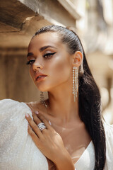 beautiful woman with dark hair in luxurious wedding dress and accessories posing in the summer...