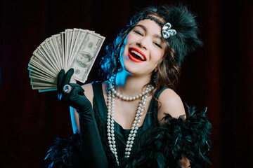 Rich luxurious woman dressed in Flappers style waves a bundle of dollars banknotes like fan....
