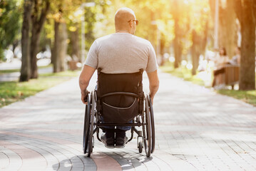 Handicapped man in wheelchair walk at the park alley