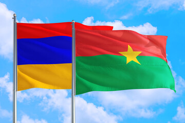 Fototapeta na wymiar Burkina Faso and Armenia national flag waving in the windy deep blue sky. Diplomacy and international relations concept.
