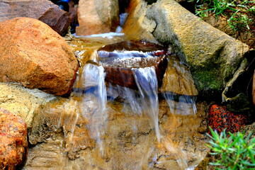 Kaskada wodna zbudowana z naturalnych kamieni i skał w przydomowym ogrodzie  