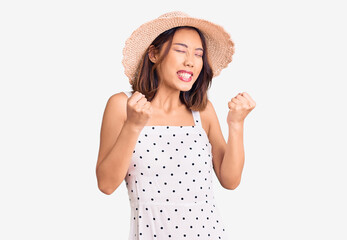 Obraz na płótnie Canvas Young beautiful chinese girl wearing summer hat excited for success with arms raised and eyes closed celebrating victory smiling. winner concept.