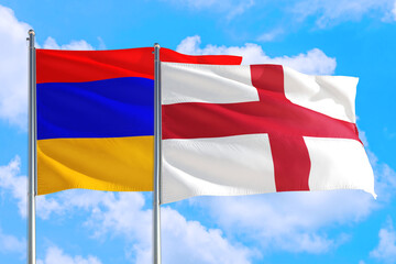 Fototapeta na wymiar England and Armenia national flag waving in the windy deep blue sky. Diplomacy and international relations concept.