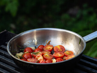 cooking tomato paste in a pan of cherry tomatoes in a frying pan. rosemary and tomato sauce.