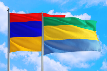Gabon and Armenia national flag waving in the windy deep blue sky. Diplomacy and international relations concept.