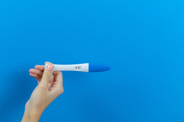 positive pregnancy test on a blue background in the hands of a girl