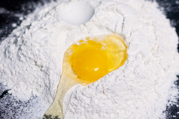 A broken chicken egg on a stack of white flour in the center of the screen.