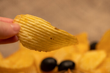 The girl's hand holds a slice of potato chips. Close up.