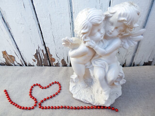 statuette of two white angels. bead heart near angels