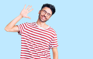 Young hispanic man wearing casual clothes waiving saying hello happy and smiling, friendly welcome gesture