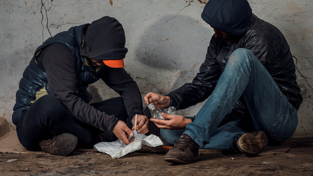 two shabby men preparing drug injection in slums