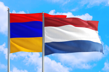 Fototapeta na wymiar Netherlands and Armenia national flag waving in the windy deep blue sky. Diplomacy and international relations concept.