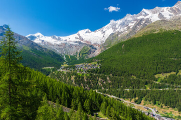 Panoramic summer view of Saas-Fee holiday village and surrounding mountains from Saas-Grund, Valais, Switzerland.