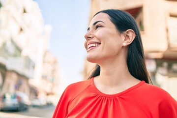 Young latin girl smiling happy walking at the city.