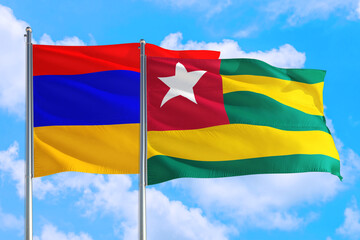 Togo and Armenia national flag waving in the windy deep blue sky. Diplomacy and international relations concept.