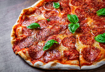 Pepperoni Pizza with Mozzarella cheese, salami, Tomato sauce, pepper, Spices and Fresh basil. Italian pizza on wooden table background