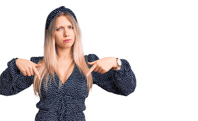 Young beautiful blonde woman wearing casual clothes pointing down looking sad and upset, indicating...