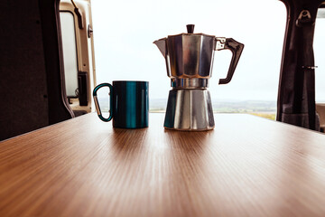Aqua bialetti coffee maker and camping mug on a wooden table in a T4 camper van