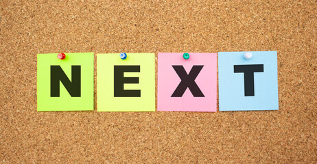 Multicolor notes with letters pinned on a cork notice board.