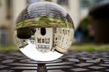 Fototapeta na wymiar Upside down large building in a glass ball on a stone parapet, blurred background