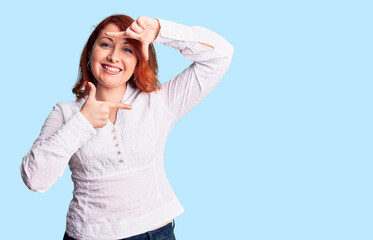 Young beautiful redhead woman wearing casual shirt smiling making frame with hands and fingers with happy face. creativity and photography concept.