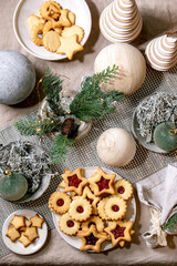 Homemade traditional Christmas Linz shortbread biscuits cookies with red jam on plate. Trend Wooden eco-friendly xmas decorations on linen tablecloth. Holiday table setting.