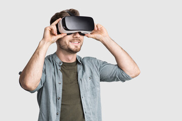 Handsome young man using virtual reality headset isolated on gray background, VR, future, gadgets, technology concept