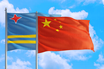 China and Aruba national flag waving in the windy deep blue sky. Diplomacy and international relations concept.