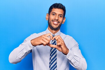 Young latin man wearing business clothes smiling in love showing heart symbol and shape with hands. romantic concept.