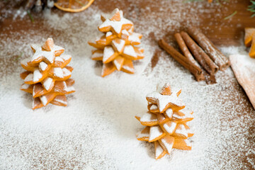 Homemade gingerbread cookies Christmas trees decorated with powdered sugar on a background of light bokeh garlands . new year's composition 2021