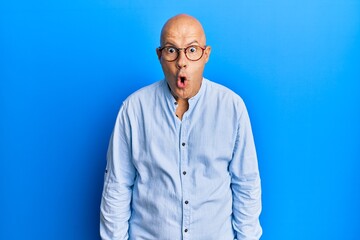 Middle age bald man wearing casual clothes and glasses afraid and shocked with surprise expression, fear and excited face.