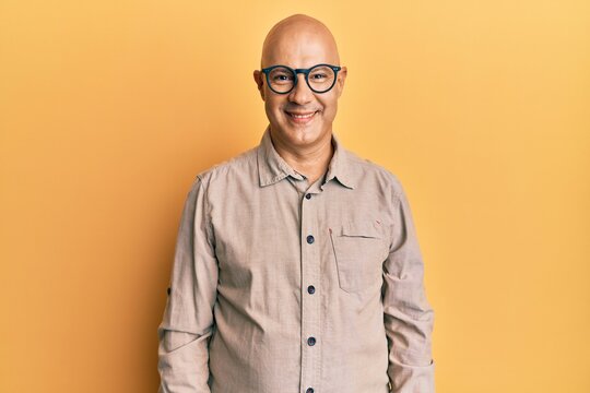 Middle age bald man wearing casual clothes and glasses with a happy and cool smile on face. lucky person.