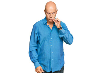 Middle age bald man wearing casual clothes mouth and lips shut as zip with fingers. secret and...