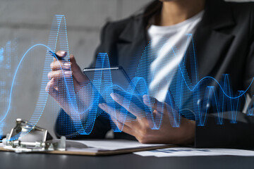 Businesswoman taking notes using smart-phone. Financial graph and chart hologram double exposure.