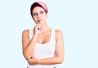 Young beautiful woman with pink hair wearing casual clothes with hand on chin thinking about question, pensive expression. smiling with thoughtful face. doubt concept.